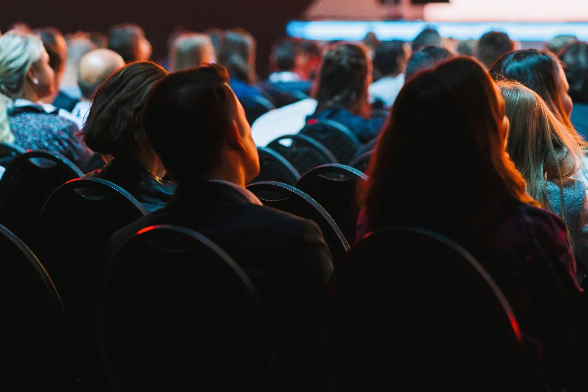 Audience members sitting in a conference hall facing a stage discussing footer design.