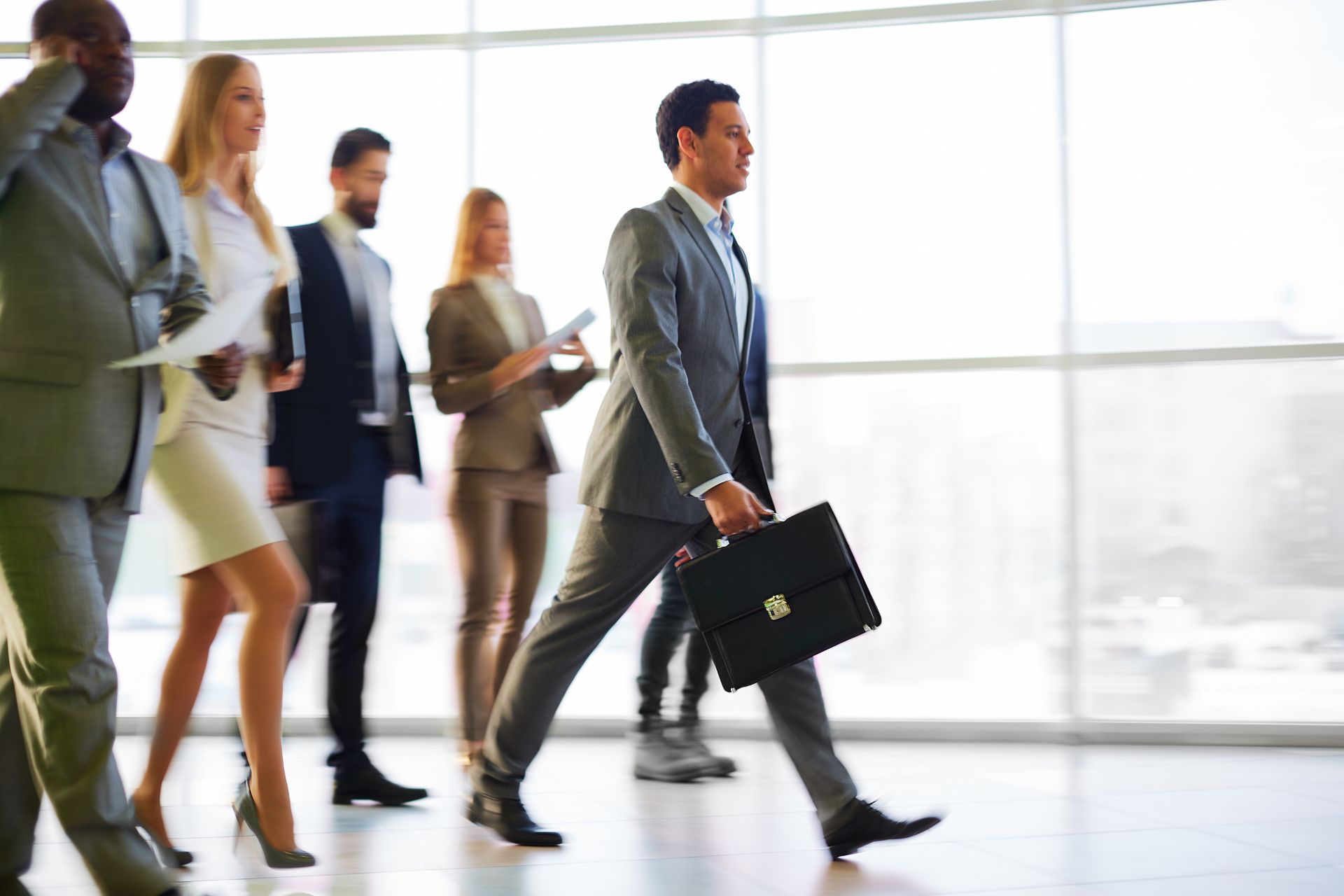 Group of leadership and business professionals walking in a modern office building.