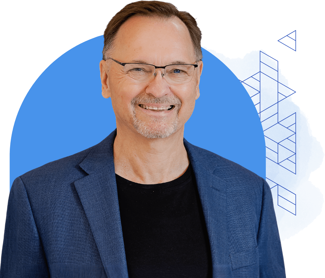 A man with glasses, dressed in a black shirt and blue blazer, is smiling in front of a blue abstract background, capturing the essence of our "About Us" page.