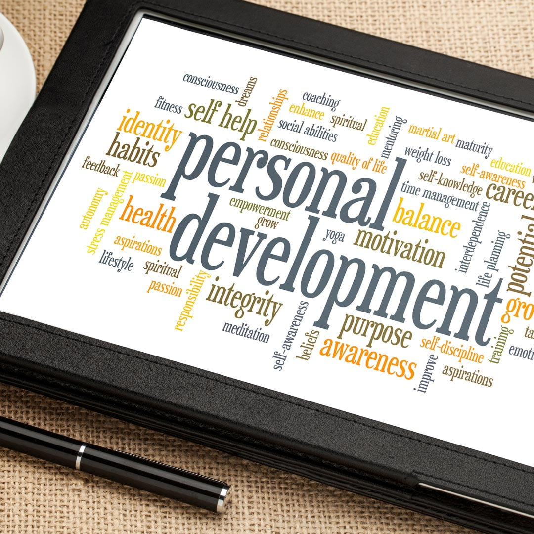 A digital tablet displaying a word cloud centered on the terms "personal development," with related words like "health," "motivation," "balance," and "awareness" for counseling services surrounding it, highlights topics integral to counseling and mental health.